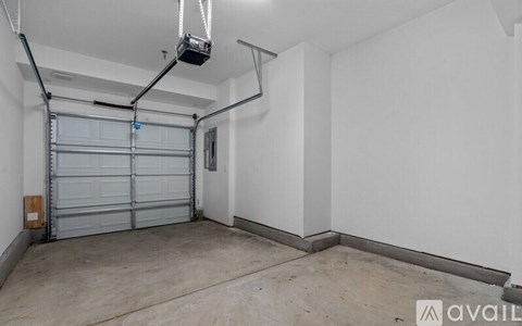 A spacious garage with a white wall and a grey door.