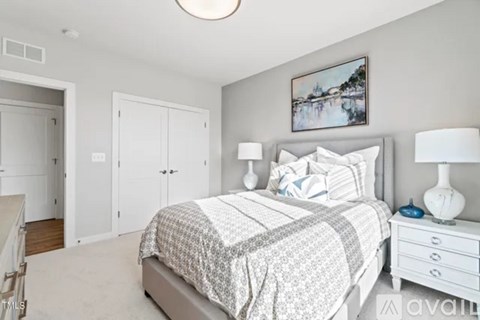 A bedroom with a bed, nightstand, and a painting on the wall.