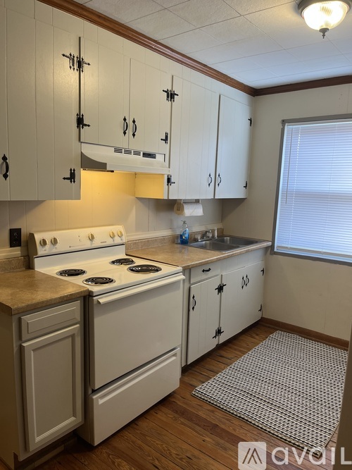 A kitchen with white cabinets and a white stove top oven.