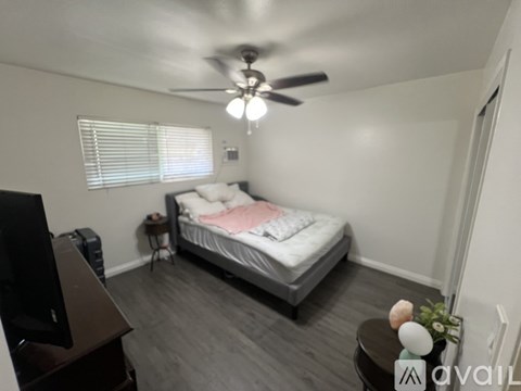 A bedroom with a bed, a television, and a ceiling fan.