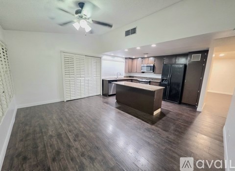 A spacious kitchen with dark wood flooring and modern appliances.
