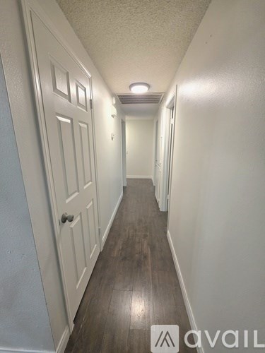 A long hallway with white doors and a light on the wall.