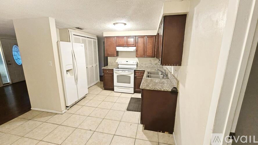 A kitchen with white appliances and brown cabinets.