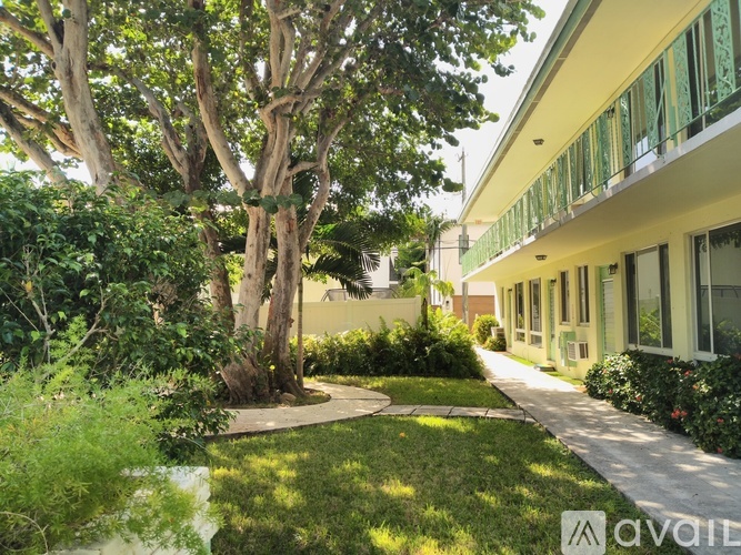 A tree in a garden with a building in the background.