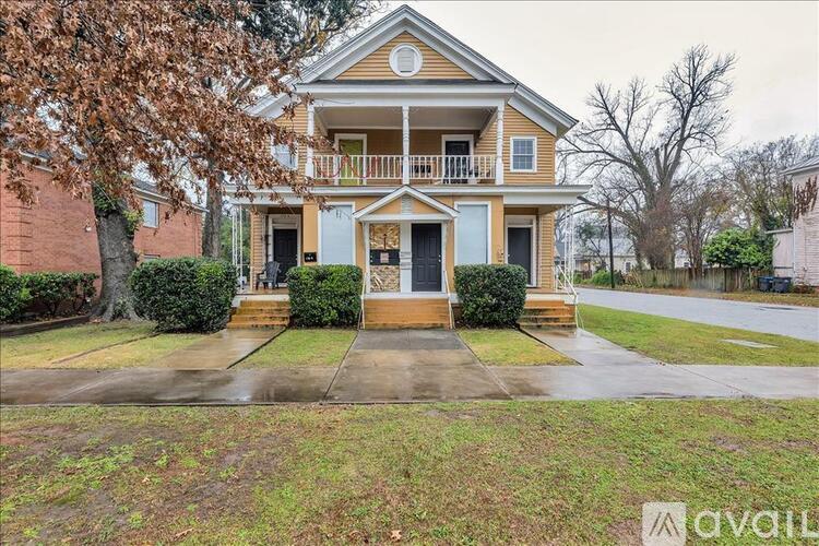 A two-story house with a front porch and a tree in front.