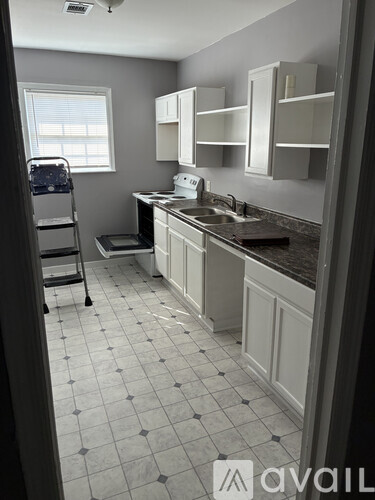 A kitchen with white cabinets and a black and white tiled floor.