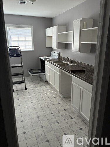 A kitchen with white cabinets and a black and white tiled floor.