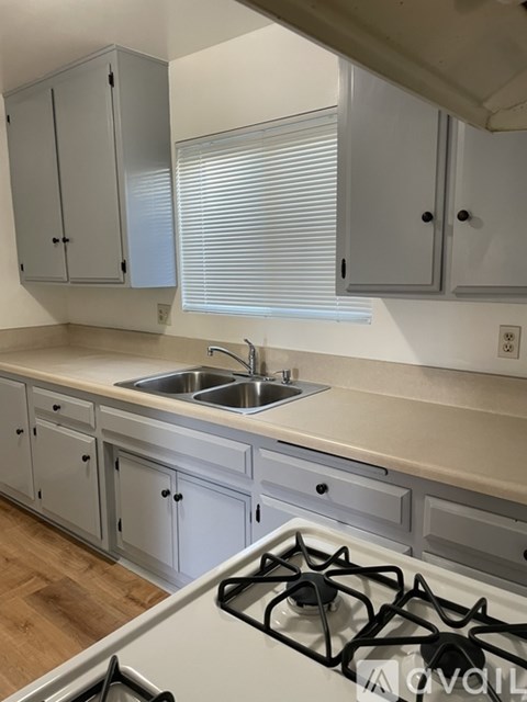 A kitchen with a white stove top oven and a white sink.