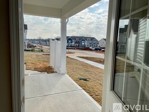 A view from a house looking out to a grassy area with a few houses in the distance.