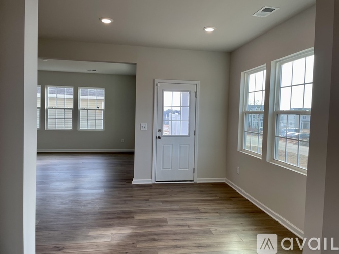A spacious room with a white door and windows on the side.