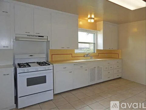 A kitchen with white cabinets and a white stove.