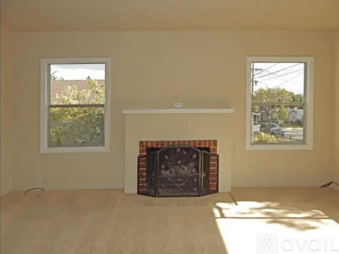 A living room with a fireplace and two windows.