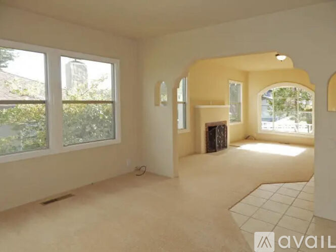 A spacious room with large windows and a fireplace.