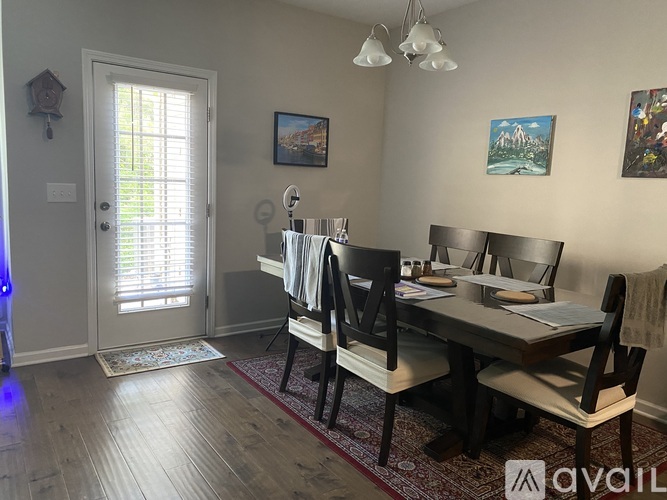 A dining room with a table set for two and a painting on the wall.