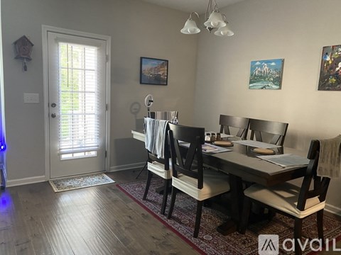 A dining room with a table set for two and a painting on the wall.