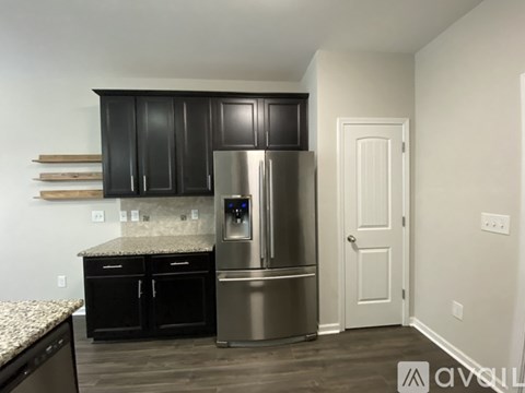 A kitchen with a stainless steel refrigerator and black cabinets.
