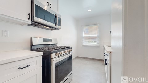 A modern kitchen with white cabinets and a stainless steel microwave above the stove.