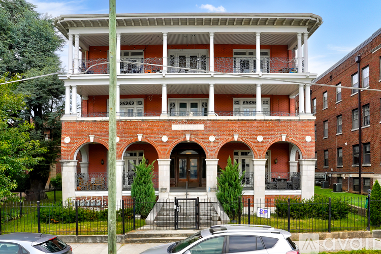 A red brick building with white trim and a balcony.