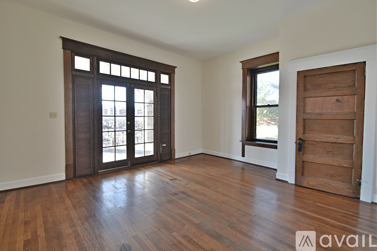 A room with wooden floors and a large window with a view of trees.