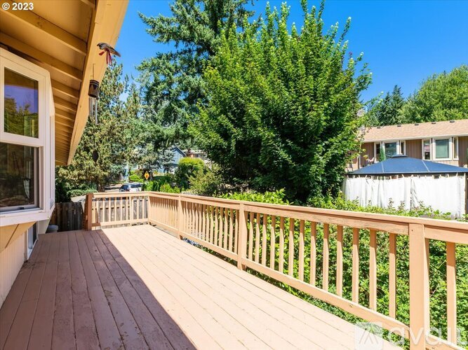 A wooden deck with a railing and trees in the background.