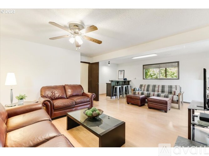 A living room with brown leather furniture and a ceiling fan.