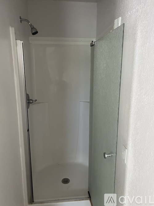 A small bathroom with a glass shower door and a white toilet.