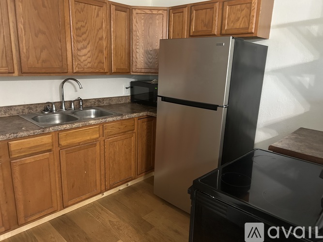 A kitchen with wooden cabinets and a stainless steel refrigerator.