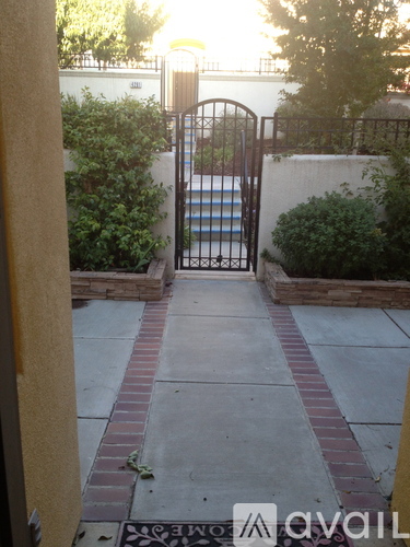 A gate with a metal handle and a brick pathway leading to a pool.