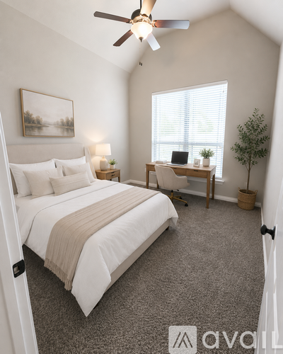 A bedroom with a large bed and a desk with a laptop on it.