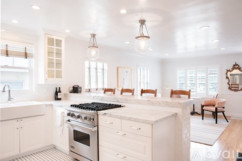 A modern kitchen with white cabinets and a marble countertop.