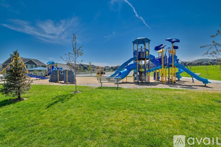 A playground with a blue and yellow slide and a green lawn.