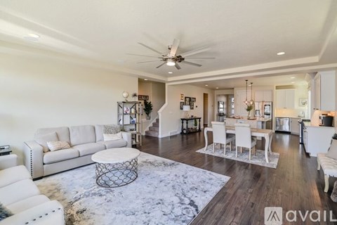 A spacious living room with a white sofa set and a dining area with a white table and chairs.