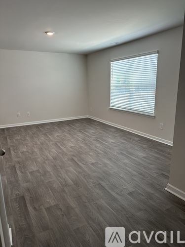 A room with wooden flooring and a window with blinds.