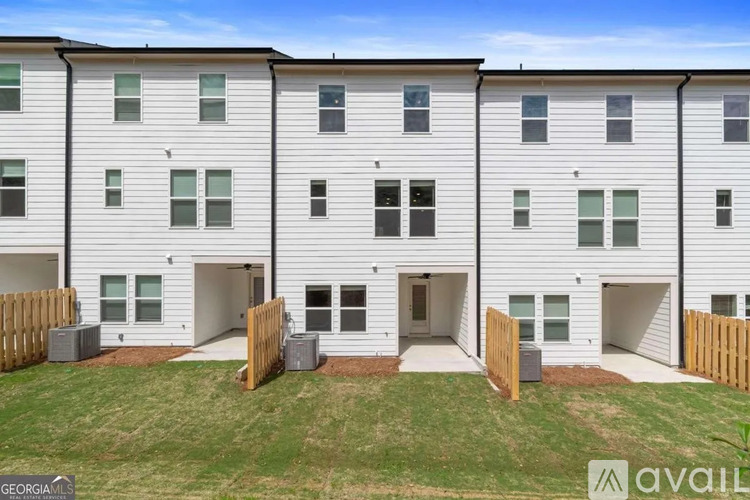 A row of white townhouses with a grassy front yard.