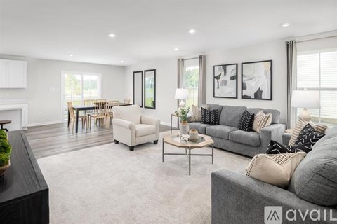 A living room with a grey couch, a coffee table, and a dining table with chairs.