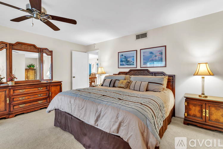 A bedroom with a large bed, a dresser, and a ceiling fan.