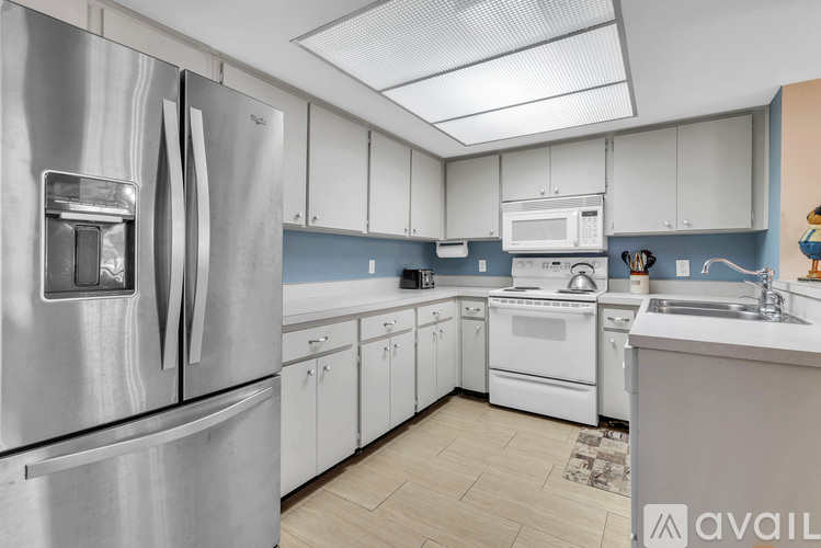 A kitchen with a stainless steel refrigerator and white cabinets.