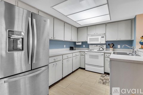 A kitchen with a stainless steel refrigerator and white cabinets.