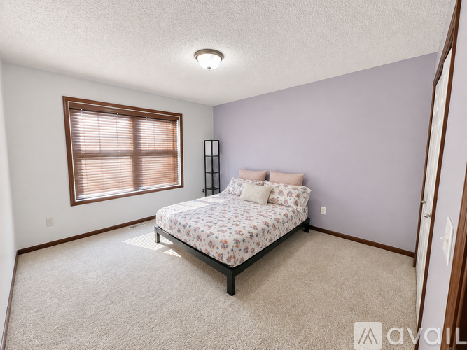 A bedroom with a bed, pillows, and a window with blinds.