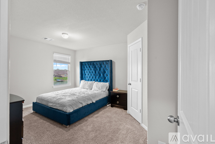 A bedroom with a blue headboard and a white bed.