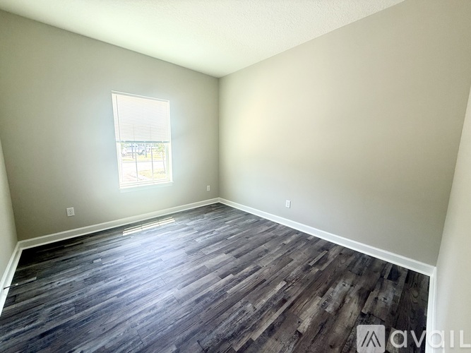 A room with wooden flooring and a window.