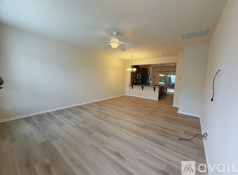 A room with a carpeted floor, a ceiling fan, and two windows.