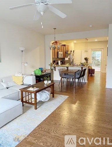 A living room with a white couch, a wooden coffee table, and a dining table with chairs.