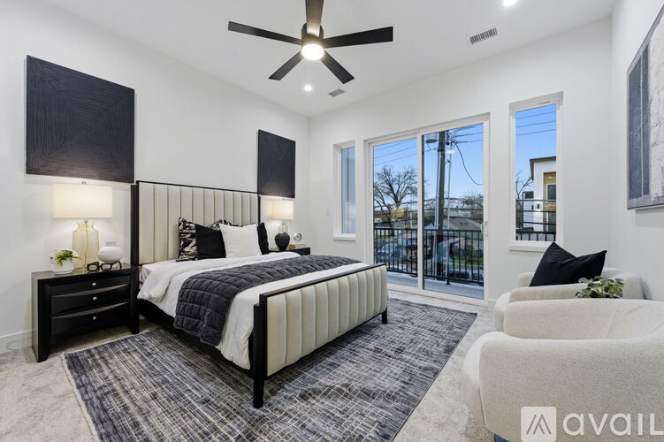 A bedroom with a large bed, a ceiling fan, and a view of the outside through the sliding glass doors.
