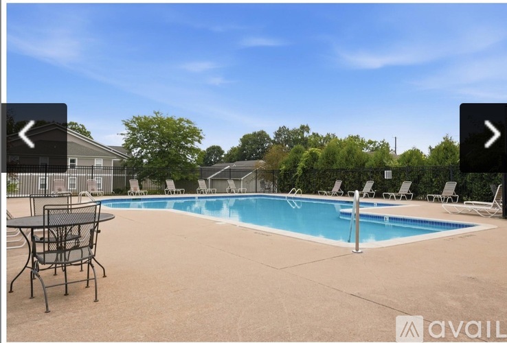 A pool with a table and chairs in front of a house.