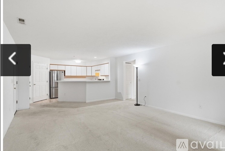 A spacious room with a carpeted floor and white walls.