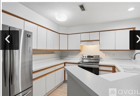 A modern kitchen with white cabinets and a stainless steel refrigerator.