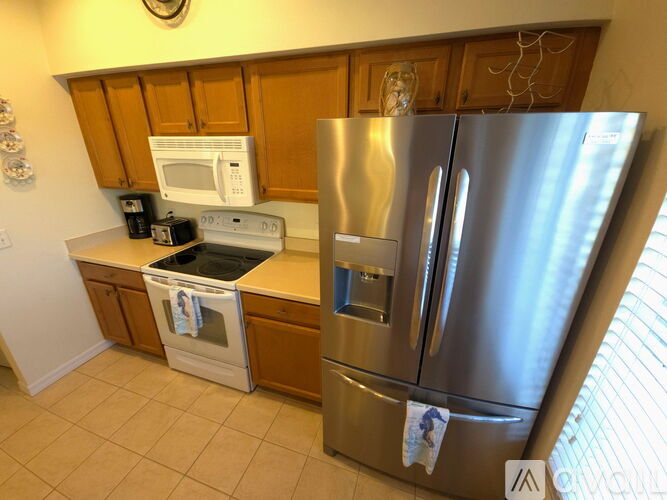 A kitchen with a stainless steel refrigerator and a white microwave.