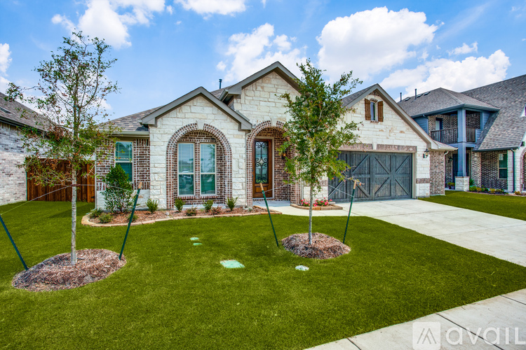 A house with a well-manicured lawn and two trees in front.