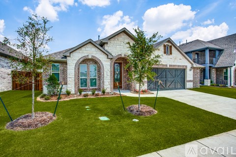 A house with a well-manicured lawn and two trees in front.